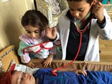 2 children dressed as medics looking at a child lying on the table